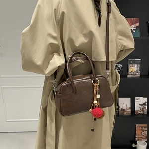 Detail of dark brown Boston bag with ethnic tassel, leather straps and silver hardware