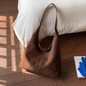 Detailed close-up of dark brown suede tote bag featuring smooth leather handles