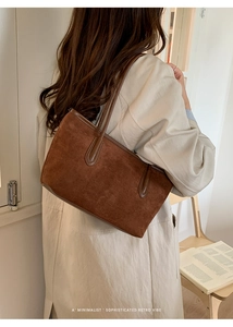 Detail of dark brown suede tote bag featuring sleek leather straps and minimalist retro design