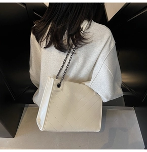 Dettaglio della borsa tote bianco crema con trama trapuntata a V e tracolla a catena