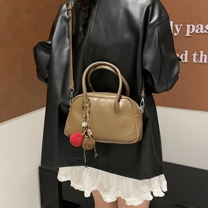 Close-up of retro brown Boston bag with plush ball charm and round handles