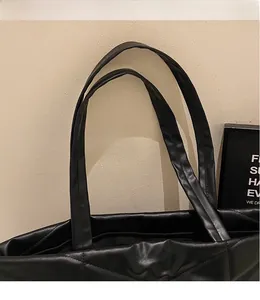 Detail of black quilted PU leather tote bag showing shoulder straps and brand logo