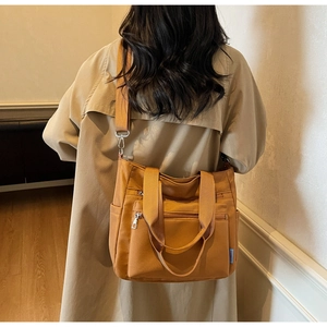 Detail of mustard yellow tote bag showing dual zip pockets and wide shoulder strap