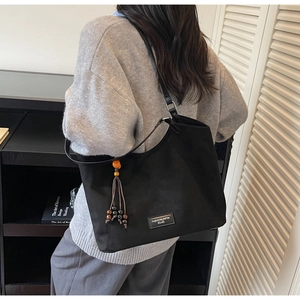 Détail du sac cabas noir avec glands en perles colorées et étiquette de logo carrée