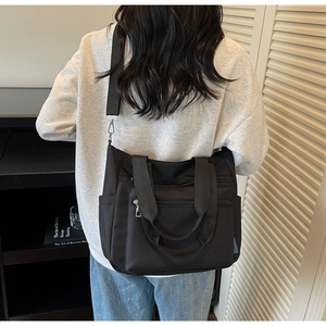 Detailed back view of a black nylon tote bag with adjustable strap and zip pockets