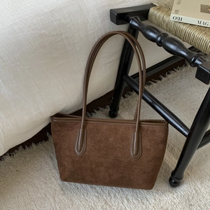 Detailed view of the dark brown suede tote bag in a cozy home setting near a bed