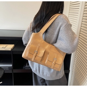 Detail view of a light brown tote bag with double square pockets and silver buckles