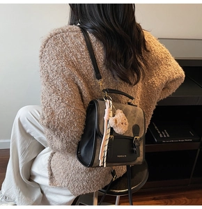 Détail d'un sac à dos vintage marron et noir avec breloque d'ours et ruban décoratif