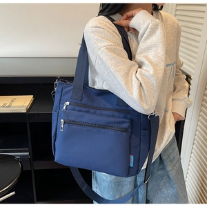 Detail of navy blue large tote bag with dual front zipper pockets and adjustable strap