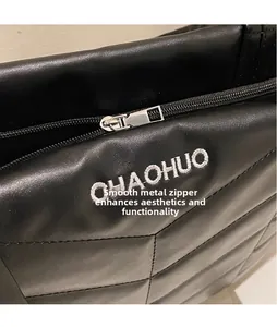 Detailed macro view of the smooth silver zipper head on black quilted leather tote bag