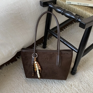 Detailed texture of dark brown faux suede tote bag with colorful wooden bead charm