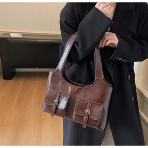 Detail view of deep brown vintage tote bag featuring two front pockets and metal buckles