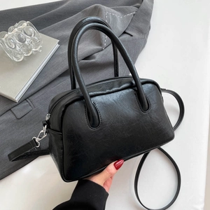 Detail of black PU leather Boston bag with vintage texture and metallic side clips