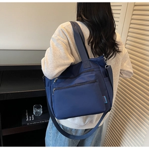 Detail of dark blue nylon tote bag with multi-zipper pockets and adjustable strap