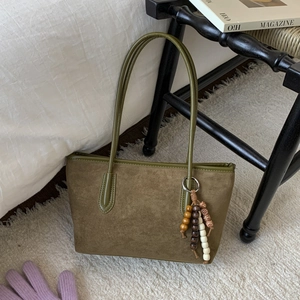 Detail view of olive suede tote bag with wooden beads decoration and leather stitching