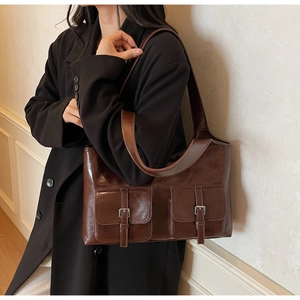 Detailed view of dark brown vintage PU leather tote bag with front flap pockets on model