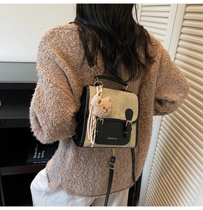 Détail d'un sac à dos rétro bicolore avec boucles dorées et charmant ours en peluche