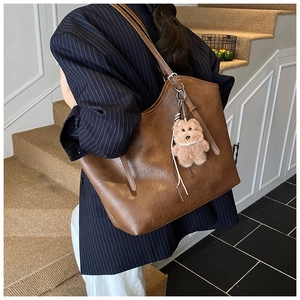 Nahaufnahme der braunen Kunstleder-Tragetasche mit Bärenanhänger und Blazer