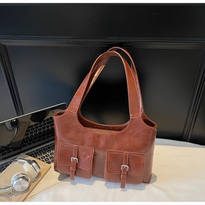 Detail of vintage brown PU leather tote bag with functional buckle pockets and shoulder straps