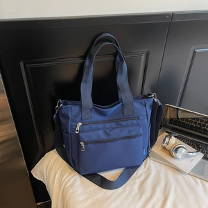 Navy nylon multi-pocket tote bag shown with office supplies on a desk for work