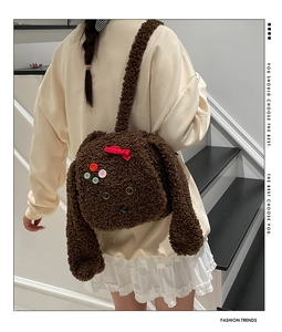 Détail du sac chiot en peluche marron foncé avec nœud rouge et texture bouclée
