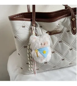 Nahaufnahme eines süßen Plüsch-Schweinchen-Anhängers an einer weißen gesteppten Tasche