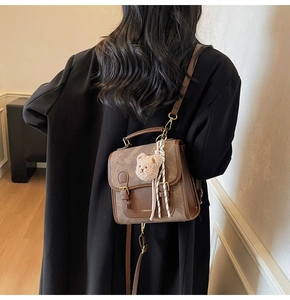 Vue détaillée d'un sac vintage marron avec un pendentif ours en peluche et un foulard