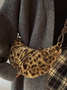 Sac croissant en peluche léopard avec bandoulière en cuir porté sur un manteau gris