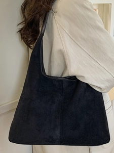 Large black faux suede tote bag with leather trim worn by a model for daily commute