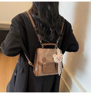 Détail d'un sac à dos vintage en cuir marron avec boucle en métal et pendentif ours