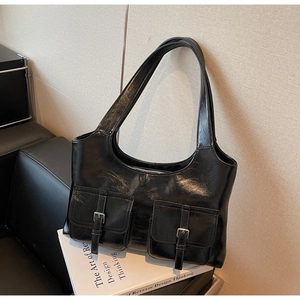 Detail of glossy black faux leather tote with dual buckled pockets and silver hardware