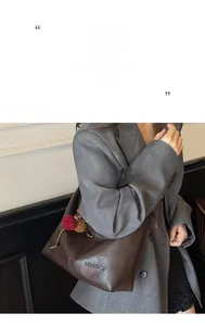 Detail of dark brown lychee grain leather tote bag with metal logo and plush charms