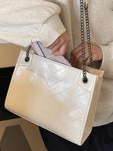 Elegante borsa tote beige trapuntata con motivo a V e tracolla a catena indossata
