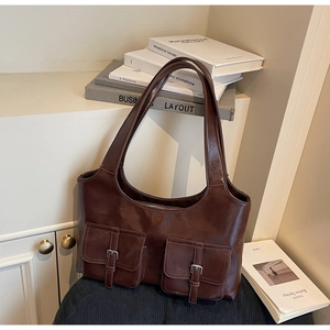 Detailed view of dark brown faux leather tote with two silver buckle front pockets