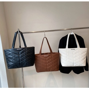 Detailed display of wave quilted tote bags in black, brown, and white with shoulder straps