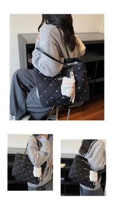 Detailaufnahme einer schwarzen Stepptasche mit weißen Schleifenmustern und Teddybär-Anhänger