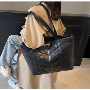 Macro view of black wave-quilted tote bag featuring white CHAOHUO lettering