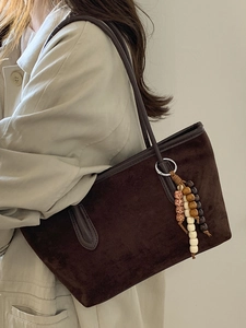 Brown suede tote bag with decorative vintage wooden beads shown as a stylish shoulder bag