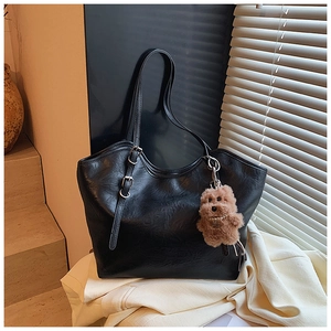 Detailansicht der schwarzen Tragetasche mit Silberbeschlägen und Teddybär-Anhänger