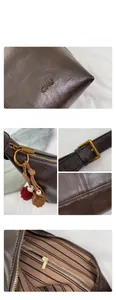 Detail view of brown leather tote showing gold hardware, logo embossing and striped lining