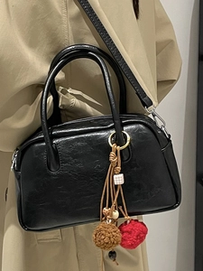 Classic black Boston bag with bohemian tassel pendant on a model in trench coat