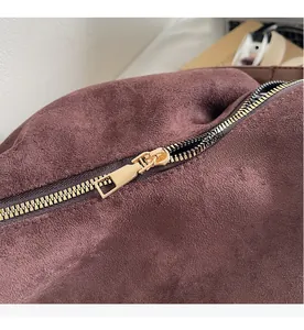 Close-up of the smooth gold-tone zipper and premium brown suede texture on the tote bag