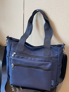 Minimalist navy blue nylon tote bag with multi-zipper pockets and adjustable shoulder strap
