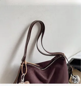 Detail of burgundy suede tote bag featuring slim leather straps and elegant tassel charms