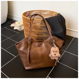 Detailansicht einer Vintage braunen Leder-Tragetasche mit süßem Plüsch-Hundeanhänger