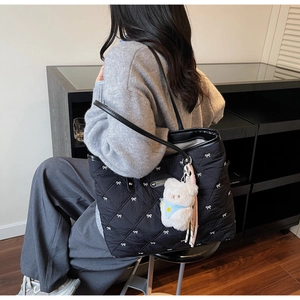 Nahaufnahme einer schwarzen gesteppten Tote-Bag mit weißer Schleifenstickerei und Bär