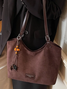 Grand sac cabas minimaliste en daim marron café avec franges porté par un modèle