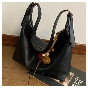 Close-up of black matte hobo bag with gold buckle detail and decorative charms