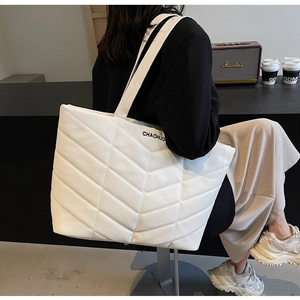 Close-up of white tote bag with V-shaped quilting detail and long shoulder strap