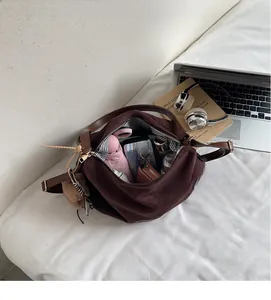 Spacious interior of a brown suede tote bag with striped lining and daily essentials